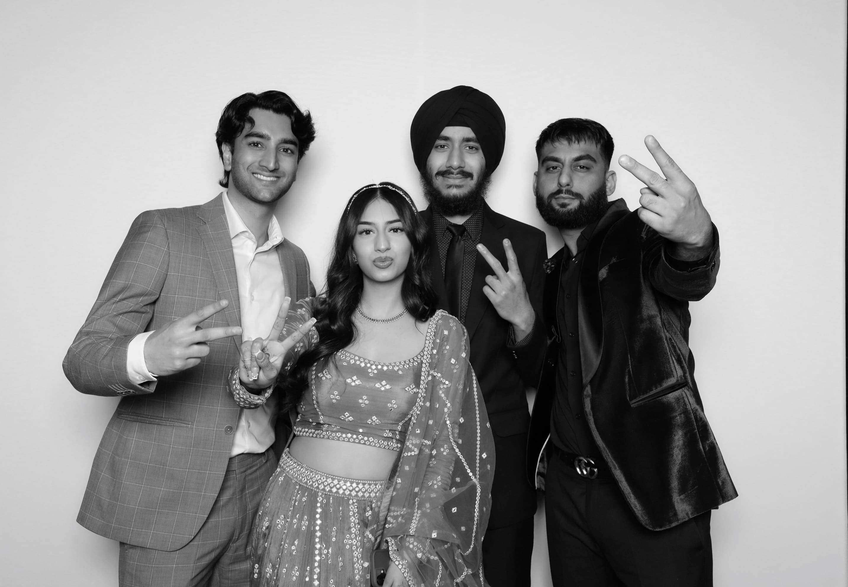 Group of four in formal wear posing at reception photo booth