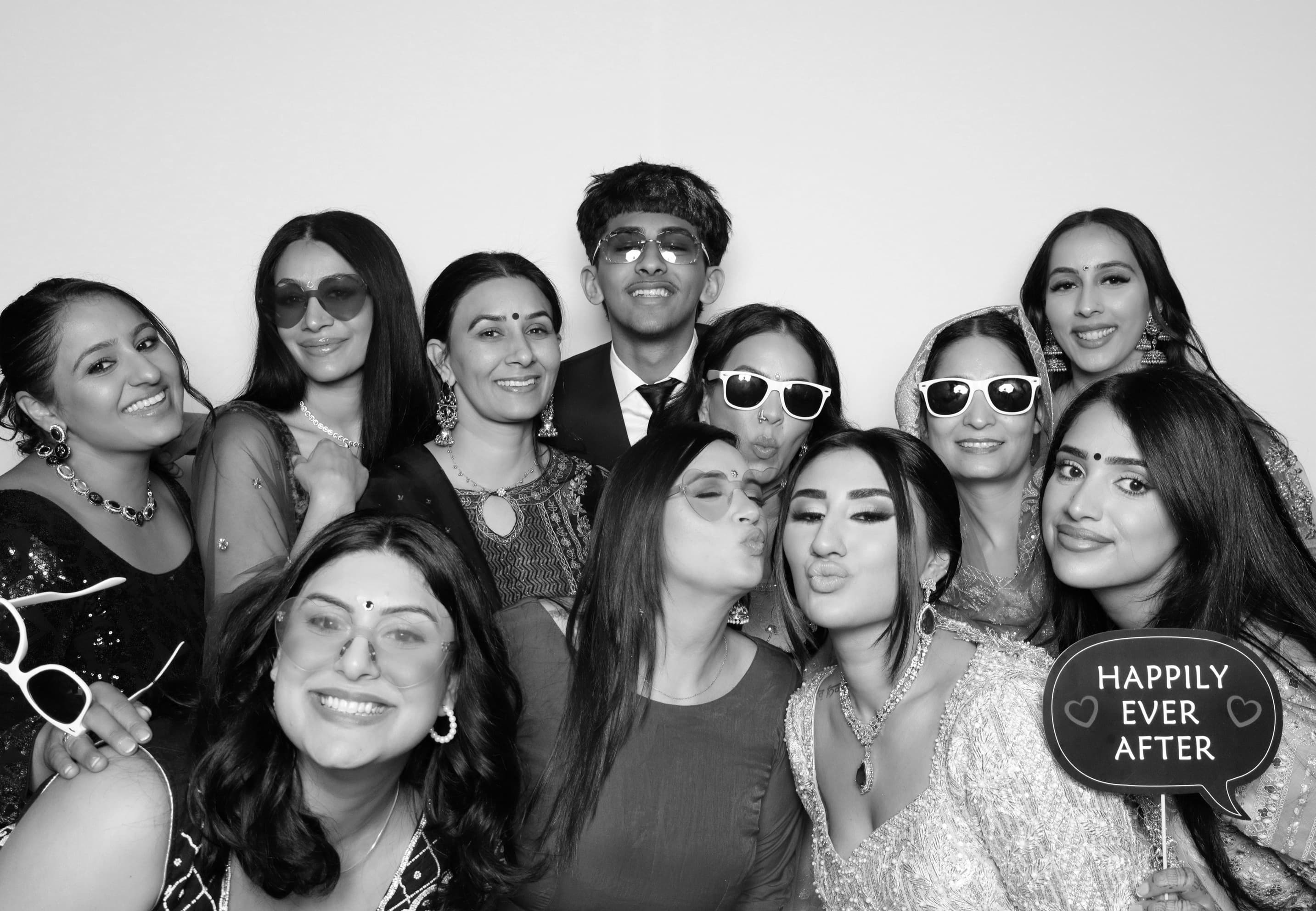 Large group at reception photo booth with Happily Ever After prop