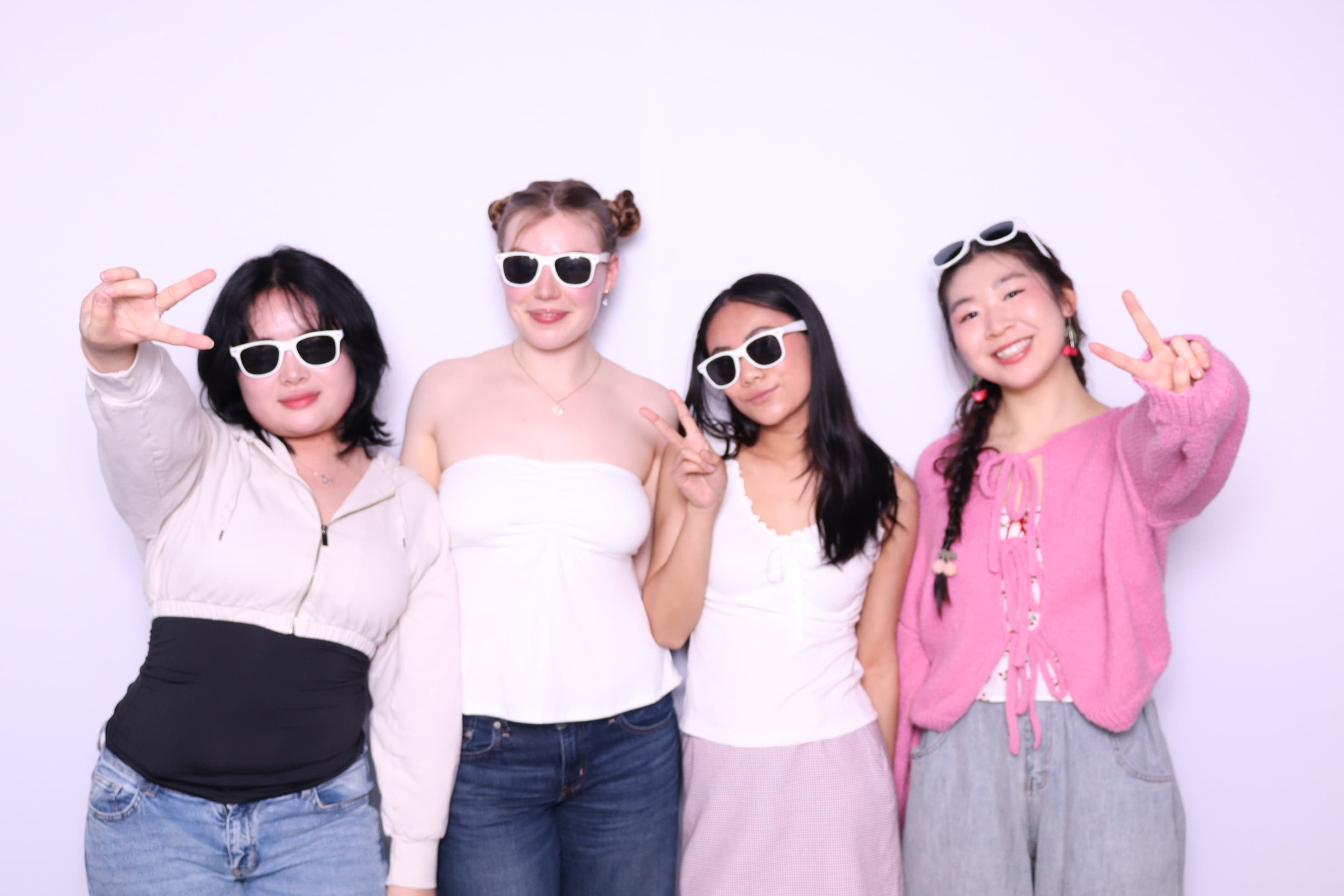Four friends with white sunglasses posing at photo booth