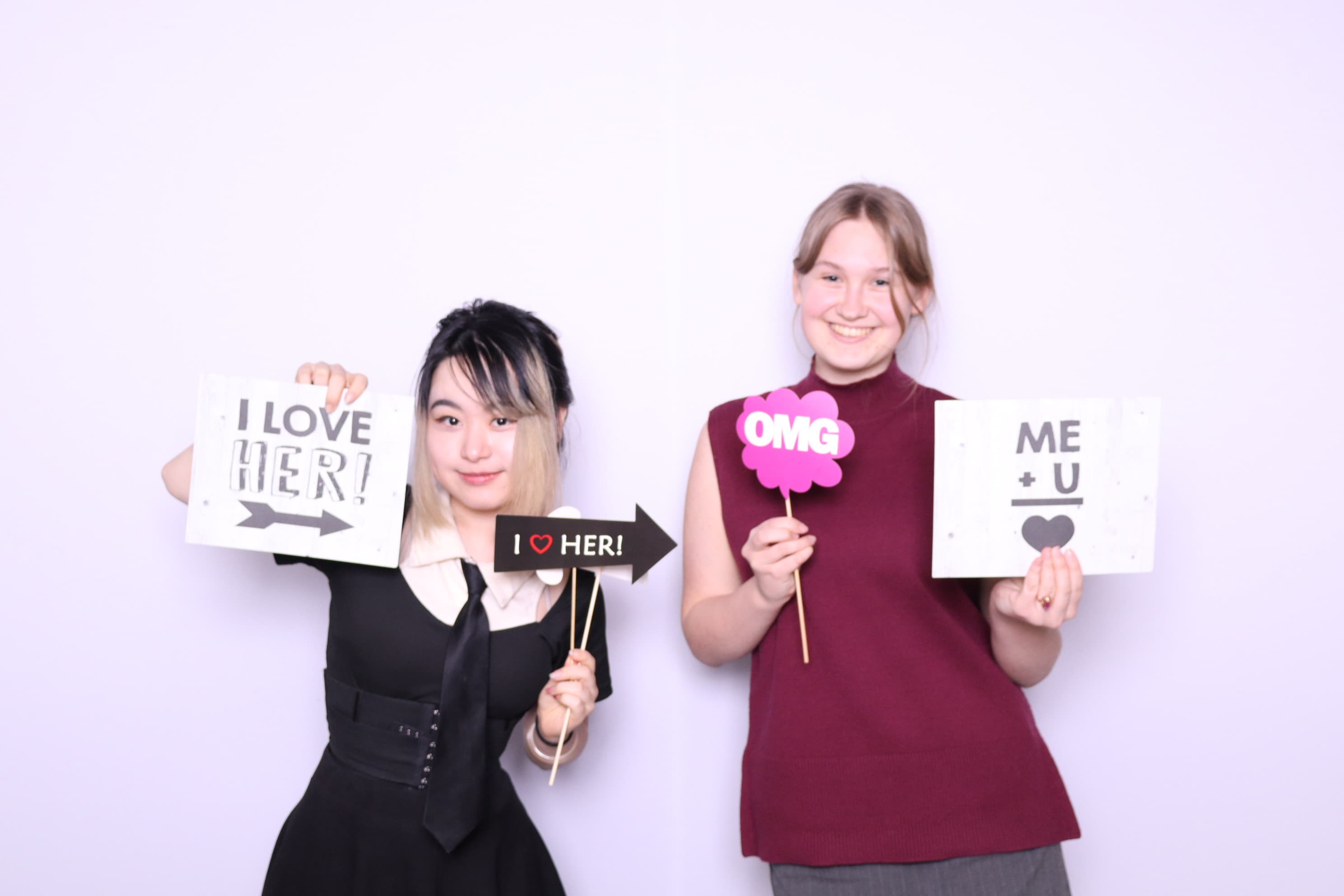 Two friends with fun signs at photo booth gathering