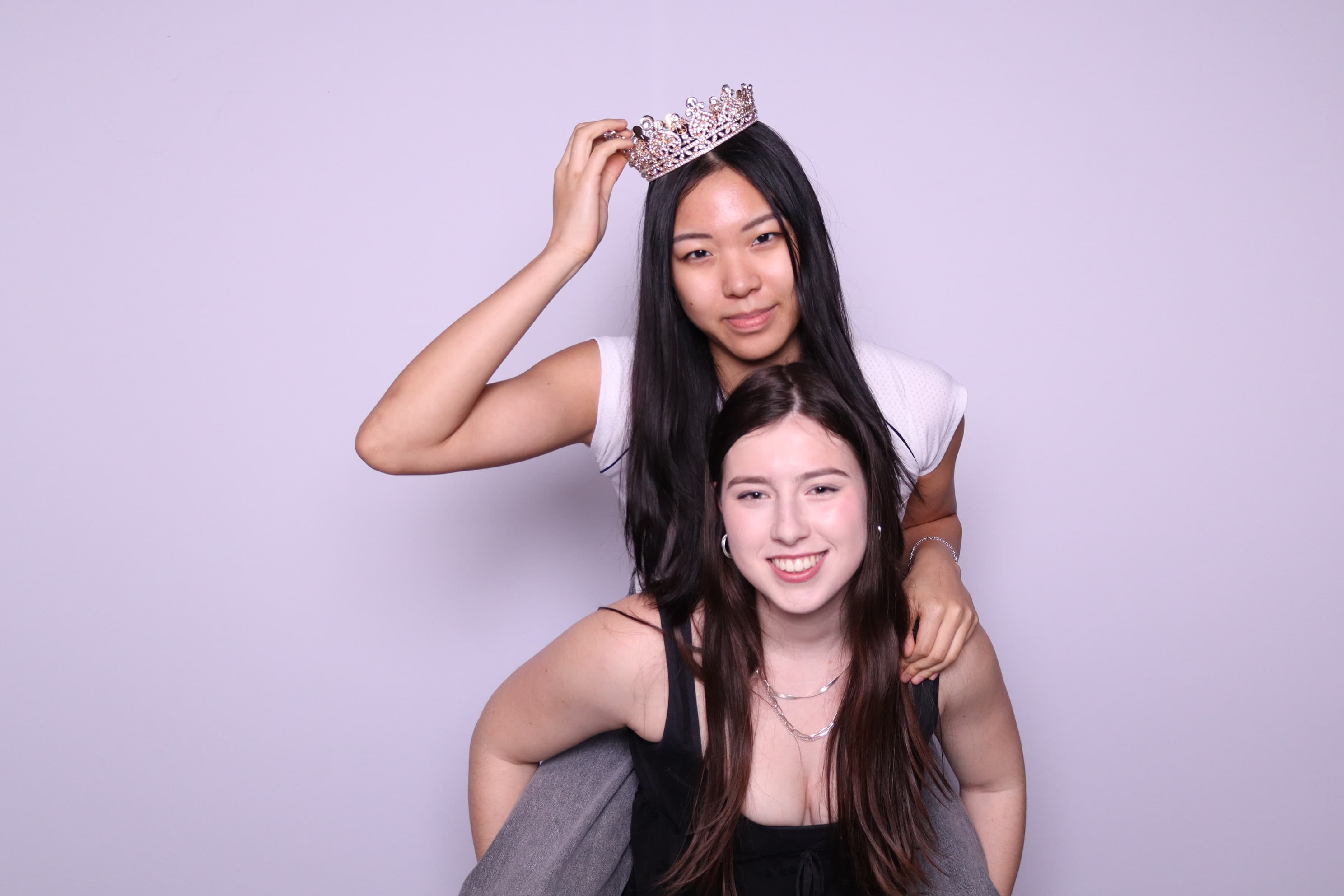 Two friends with crown prop at photo booth event