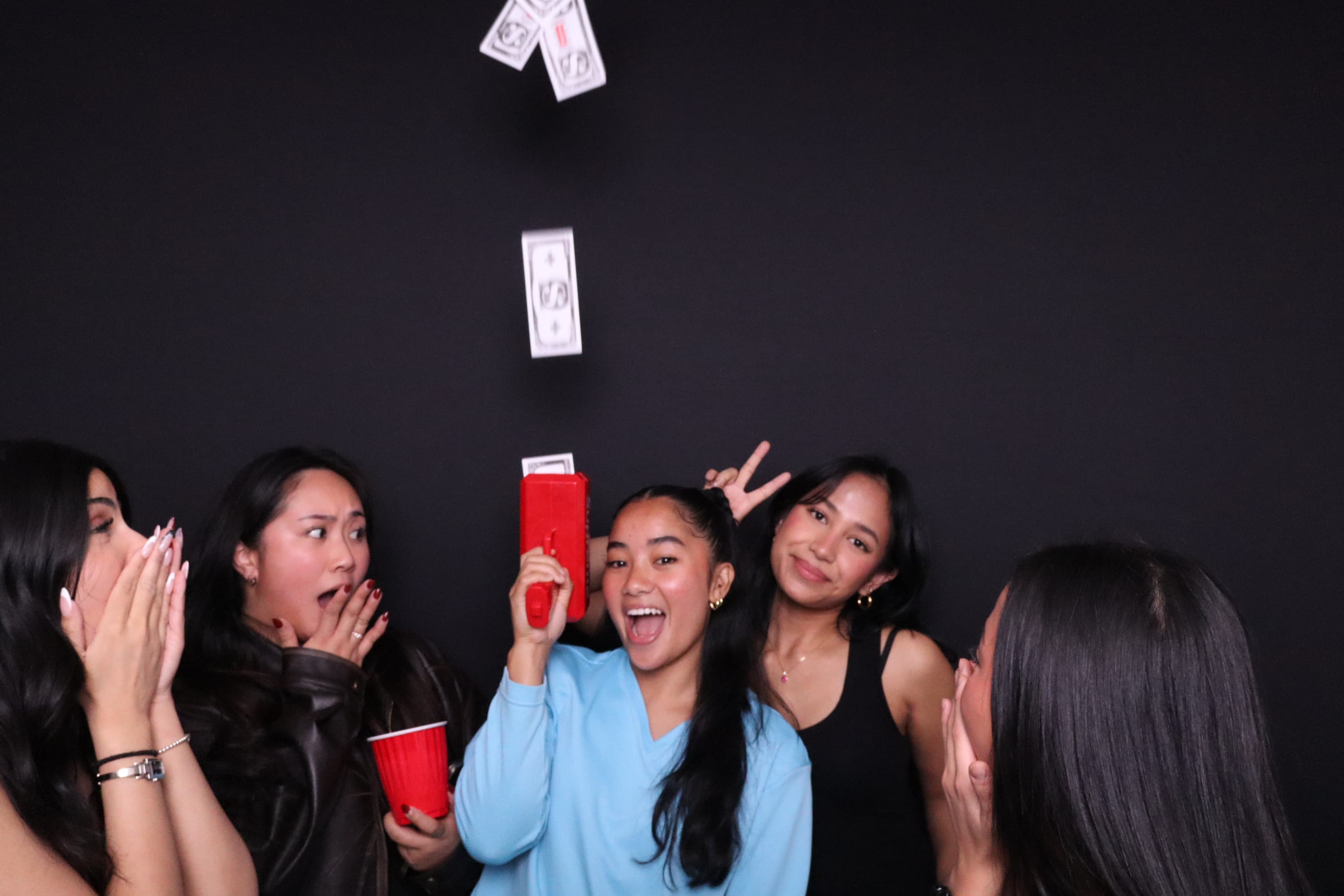 Girls throwing money props at birthday photo booth Vancouver